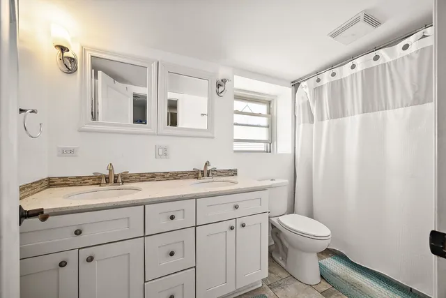 a bathroom with a granite countertop sink a toilet and a mirror