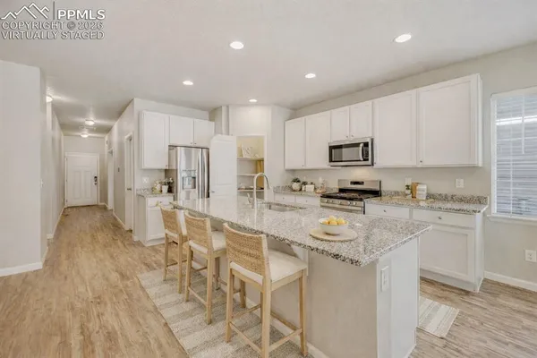 a large kitchen with stainless steel appliances granite countertop a lot of counter space and wooden floors