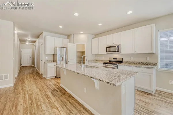 a large kitchen with stainless steel appliances granite countertop a lot of counter space and wooden floor
