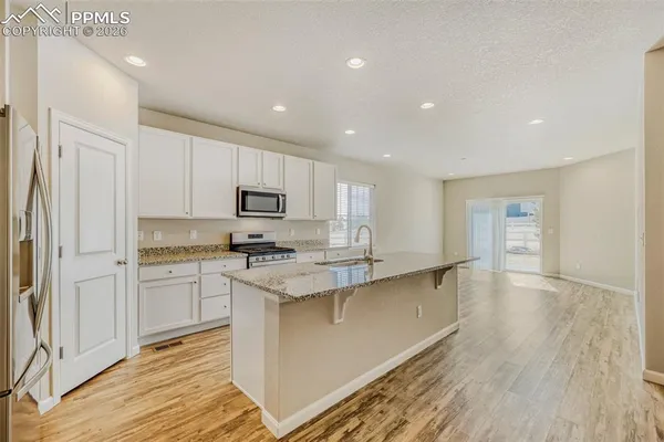 a view of a kitchen with kitchen island a sink dishwasher and a stove with wooden floor