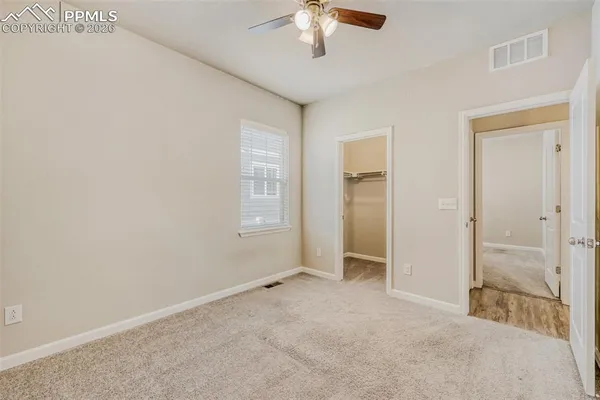 an empty room with chandelier fan and windows