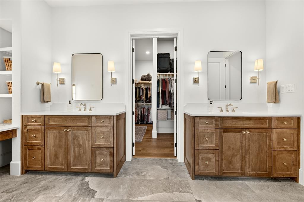 10932 Gregory Road Sanger, TX 76266 - Photo 22 of 40 Dual vanity setup featuring wood cabinetry with gold hardware, white countertops, and wall-mounted sconces