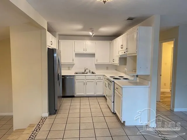 a kitchen with a white cabinets a sink a stove a refrigerator and a window