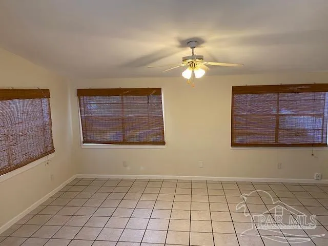 a view of an empty room with window and chandelier fan