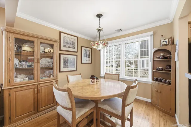 a dining room with wooden floor a chandelier a wooden table and chairs