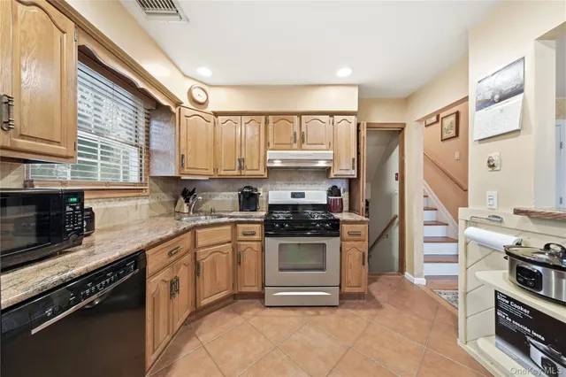 a kitchen with stainless steel appliances granite countertop a stove top oven a sink and a refrigerator