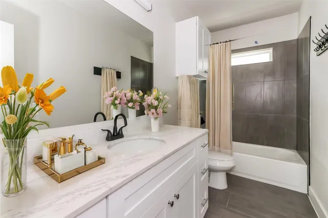 a bathroom with a granite countertop sink a toilet and shower