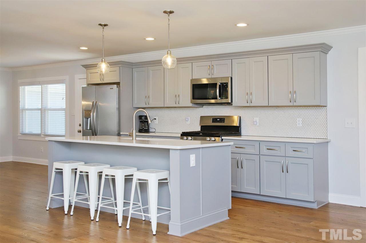 1308 East Lane Street Raleigh, NC 27610 - Photo 7 of 21 a kitchen with stainless steel appliances granite countertop a stove top oven a sink a window and white cabinets