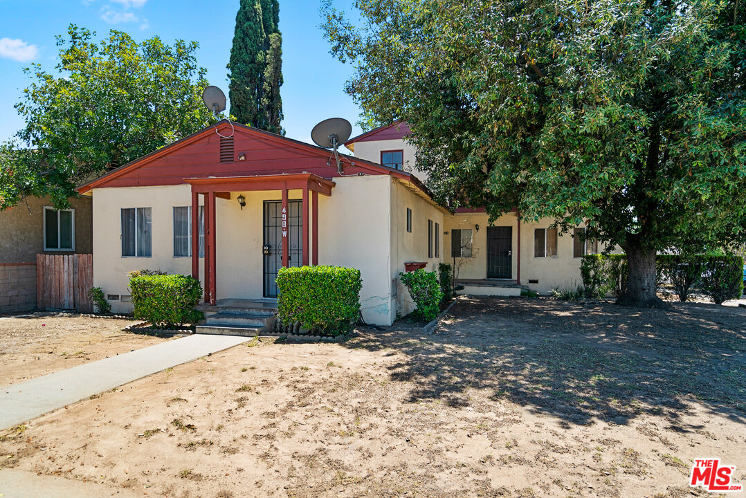a front view of a house with a yard and a tree