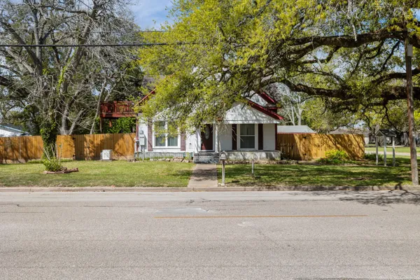 a front view of a house with a garden and tree