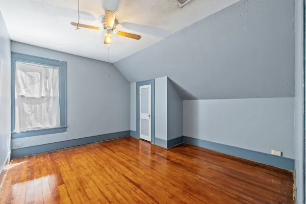 a view of a hallway with wooden floor and a bathroom