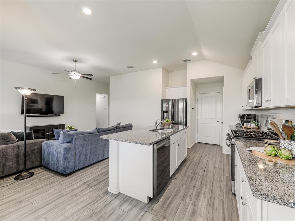 4517 Ashmark Road Aubrey, TX 76227 - Photo 22 of 26 a large kitchen with stainless steel appliances granite countertop a stove oven a sink dishwasher and a refrigerator with wooden floor
