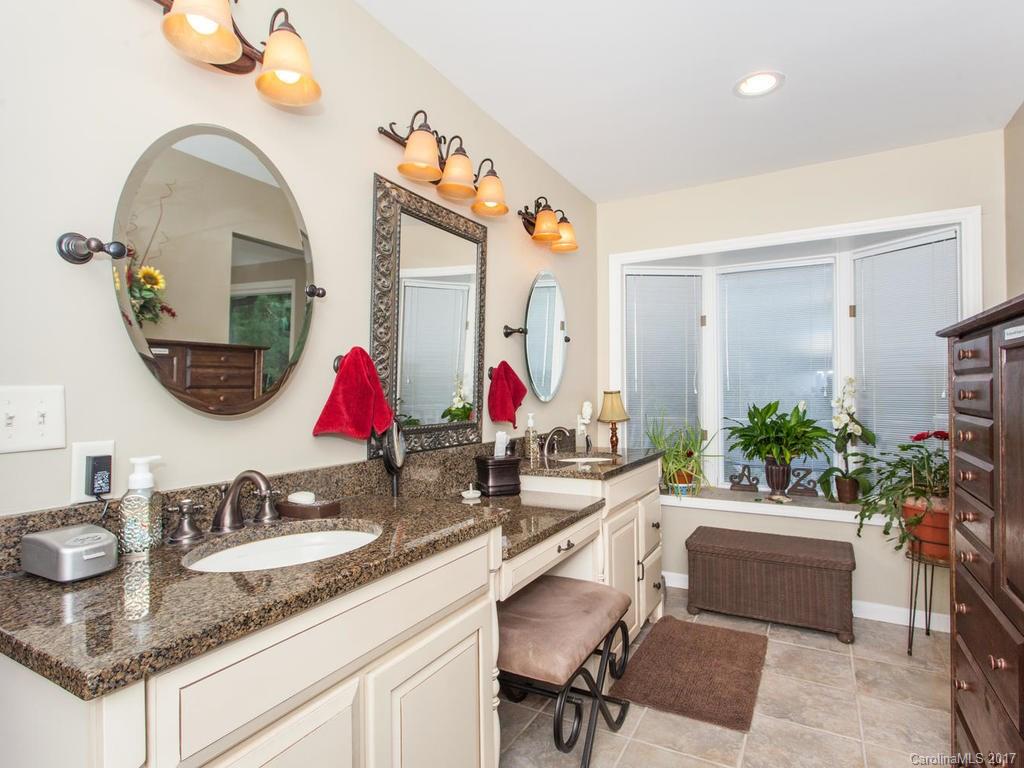 3419 Hebron Road Hendersonville, NC 28739 - Photo 10 of 22 a bathroom with a granite countertop sink a mirror and a shower