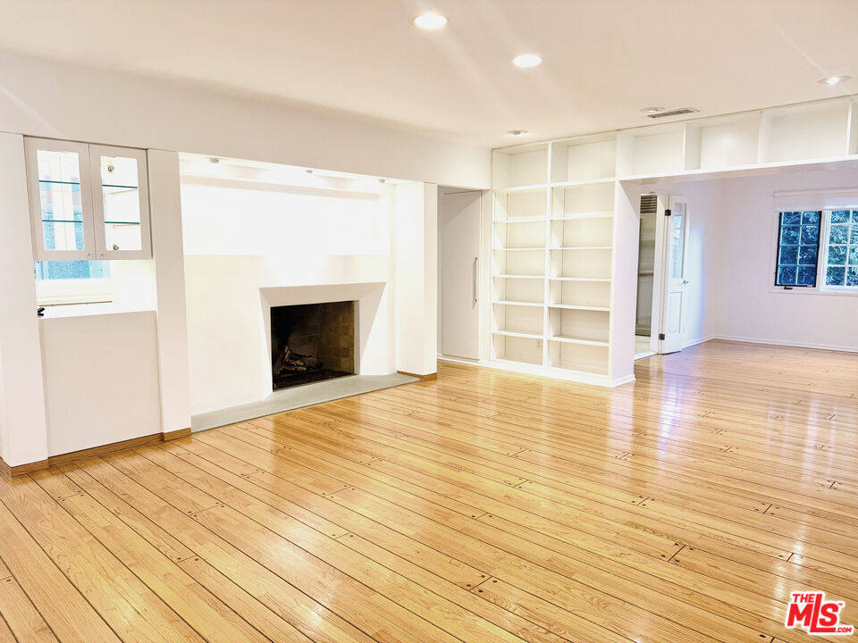 4031 Hollyline Avenue Sherman Oaks, CA 91423 - Photo 3 of 31 a view of an empty room with wooden floor and a fireplace