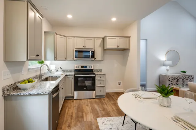 a kitchen with a refrigerator a stove a sink and white cabinets with wooden floor