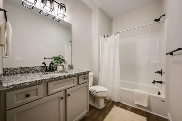 a bathroom with a granite countertop sink a toilet a mirror and shower