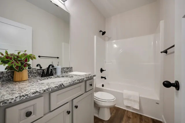 a bathroom with a granite countertop sink a toilet and shower