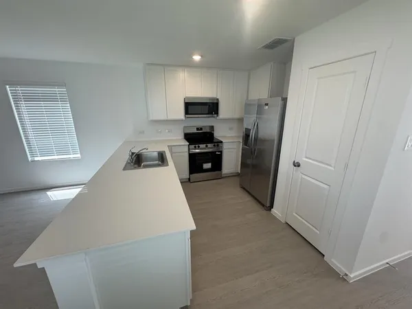 a kitchen with a refrigerator a stove top oven and cabinets