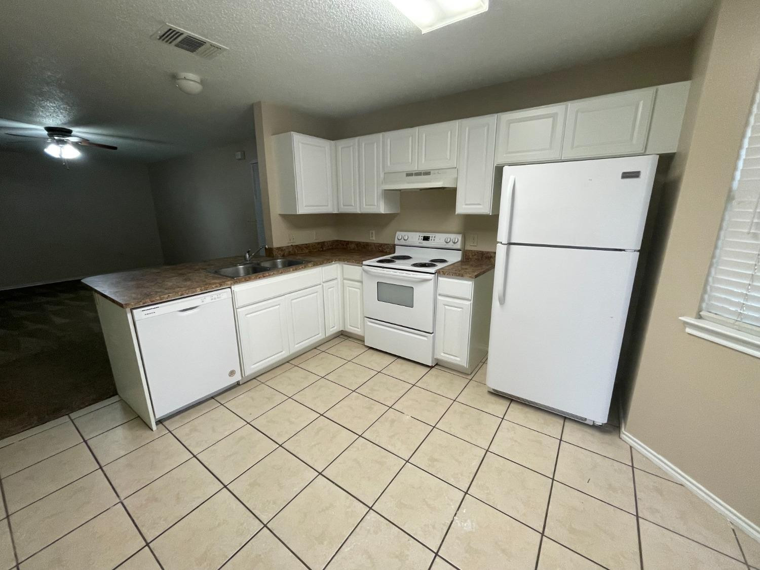 5827 6th Street, Unit A Lubbock, TX 79416 - Photo 3 of 10 a kitchen with white cabinets and white appliances