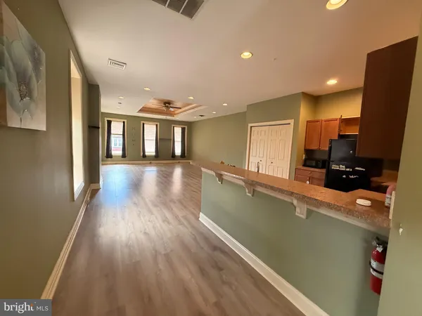 a living room with stainless steel appliances furniture a refrigerator and a kitchen view
