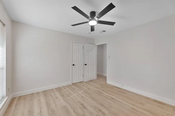 an empty room with wooden floor and ceiling fan