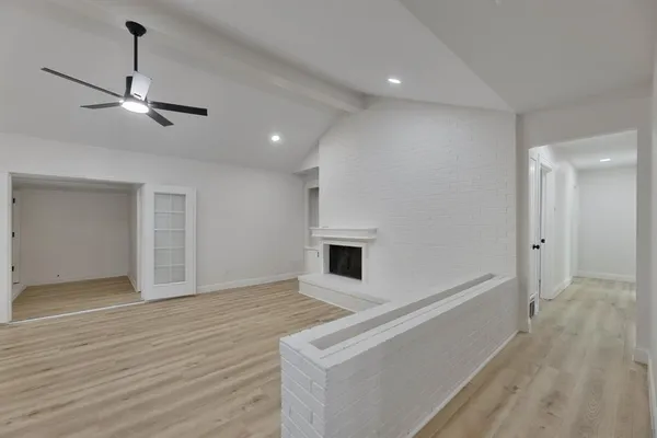 a view of an empty room with wooden floor and a ceiling fan