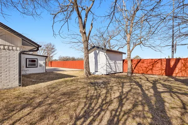 a backyard of a house with wooden fence and large trees