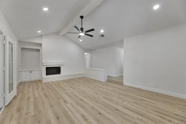 an empty room with wooden floor and ceiling fan