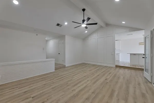 an empty room with wooden floor ceiling fan and windows