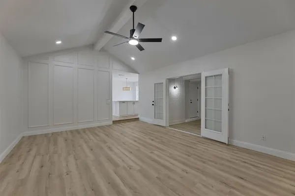 an empty room with wooden floor and ceiling fan