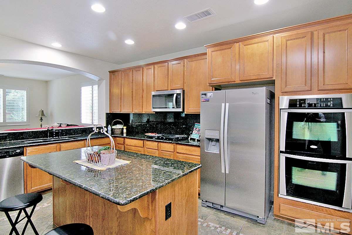 11215 Parma Way Reno, NV 89521 - Photo 12 of 22 a kitchen with stainless steel appliances granite countertop a refrigerator a stove and a sink with wooden floor