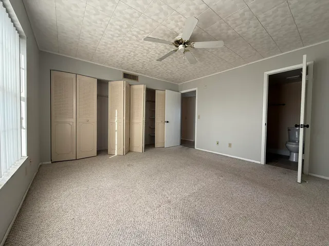 an empty room with windows and fan