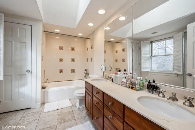 a bathroom with a double vanity sink a mirror and a bathtub