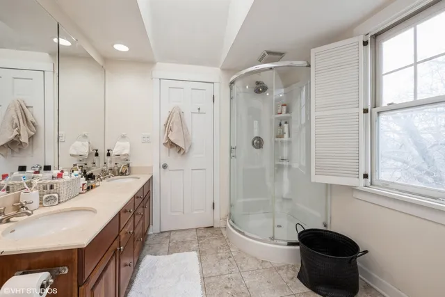 a bathroom with a double vanity sink a toilet and shower