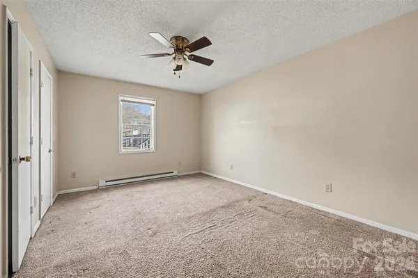 an empty room with windows and fan