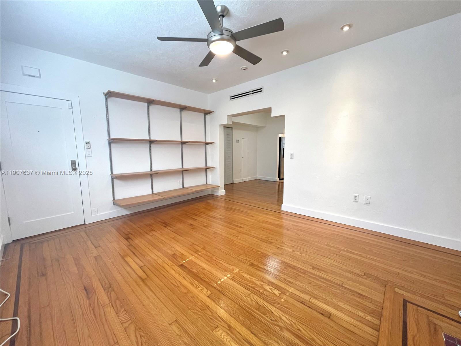 1307 Euclid Avenue, Unit 2 Miami Beach, FL 33139 - Photo 4 of 13 an empty room with wooden floor closet ceiling fan and windows