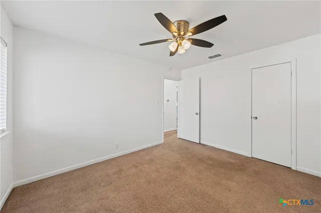 an empty room with a window and a ceiling fan