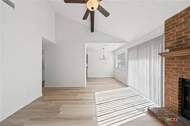 a view of a livingroom with a fireplace a ceiling fan and wooden floor