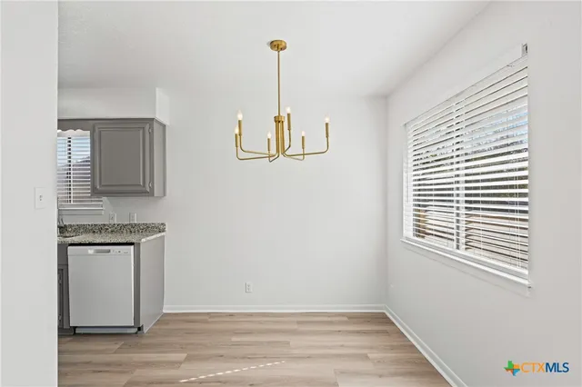 an empty room with wooden floor fireplace and windows