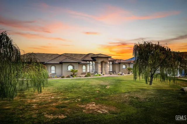 a view of a big house with a big yard and palm trees