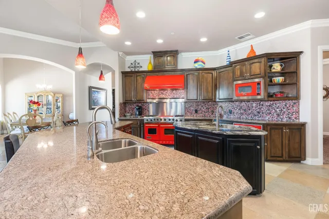 a kitchen with stainless steel appliances granite countertop a refrigerator a stove and a sink
