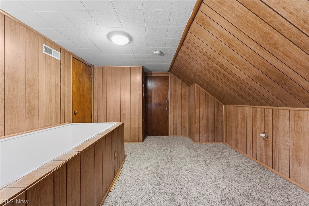 5615 Snow Road Parma, OH 44129 - Photo 23 of 39 Additional living space featuring wood walls, light colored carpet, and lofted ceiling
