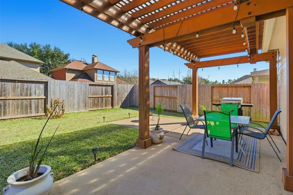 a view of a patio with table and chairs near a barbeque
