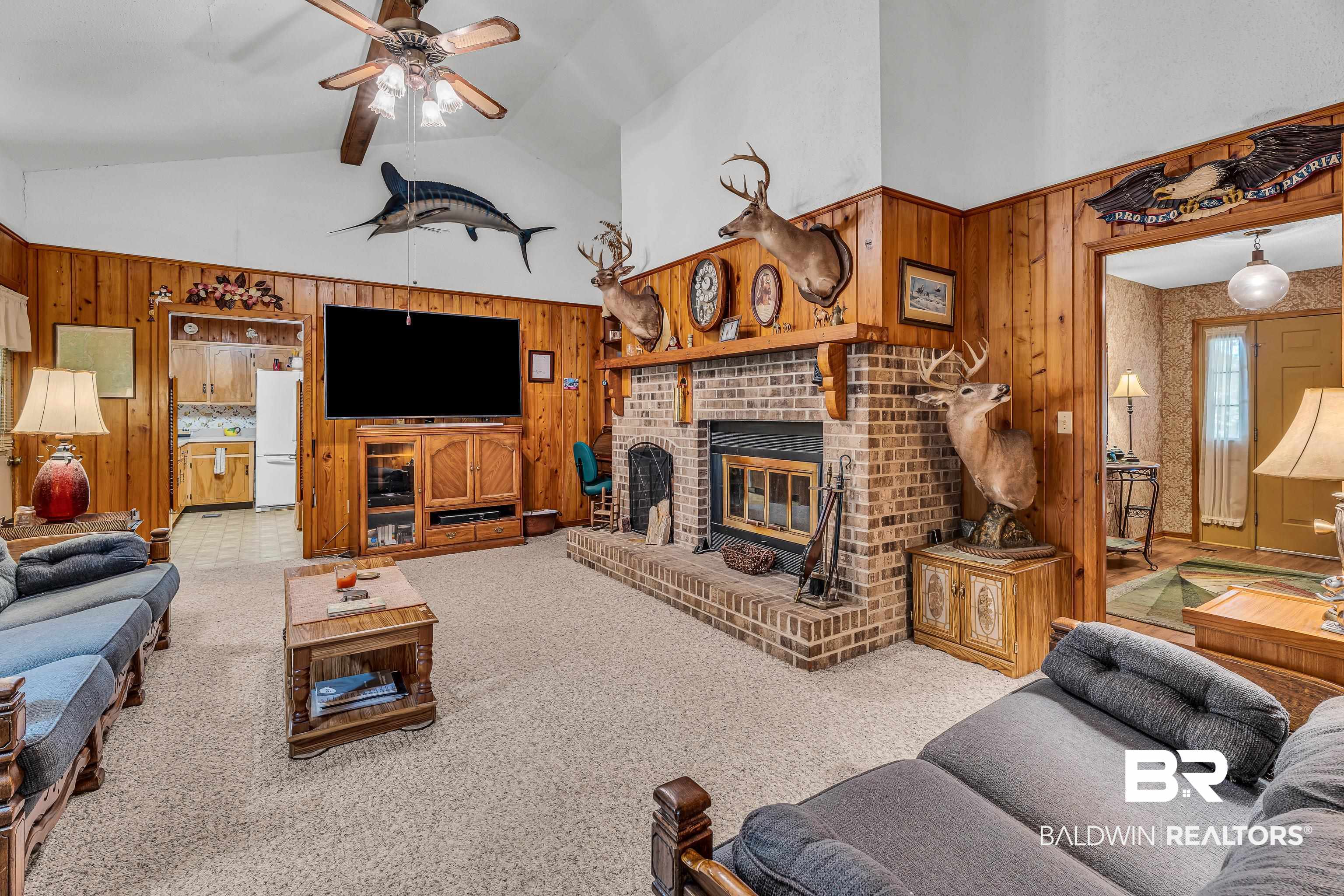 72075 Highway 59 Little River, AL 36550 - Photo 7 of 40 Living room with high vaulted ceiling, a brick fireplace, wood walls, light colored carpet, and ceiling fan