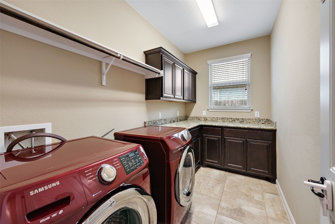 2000 Manada Trail Leander, TX 78641 - Photo 17 of 36 Functional laundry room featuring a convenient folding counter, storage cabinetry, and durable tile flooring.