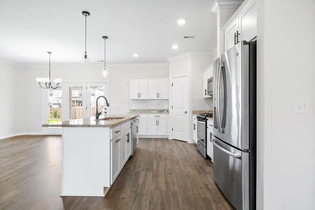 a kitchen with stainless steel appliances granite countertop a refrigerator a sink dishwasher a stove and a refrigerator