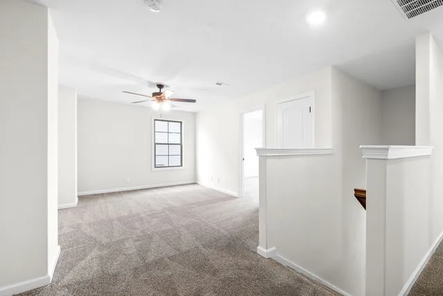 an empty room with windows and fan