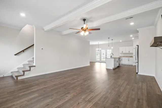 a kitchen with stainless steel appliances granite countertop a refrigerator a sink dishwasher a stove and a wooden floors