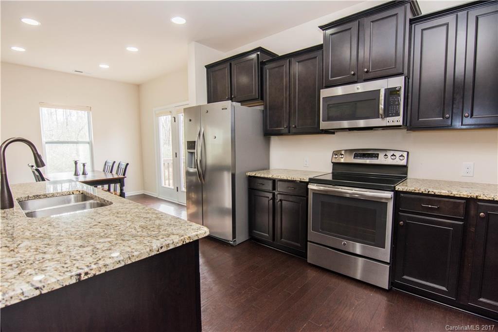 1689 Beleek Ridge Lane Clover, SC 29710 - Photo 5 of 24 a kitchen with granite countertop wooden cabinets a refrigerator and a stove top oven with wooden floor