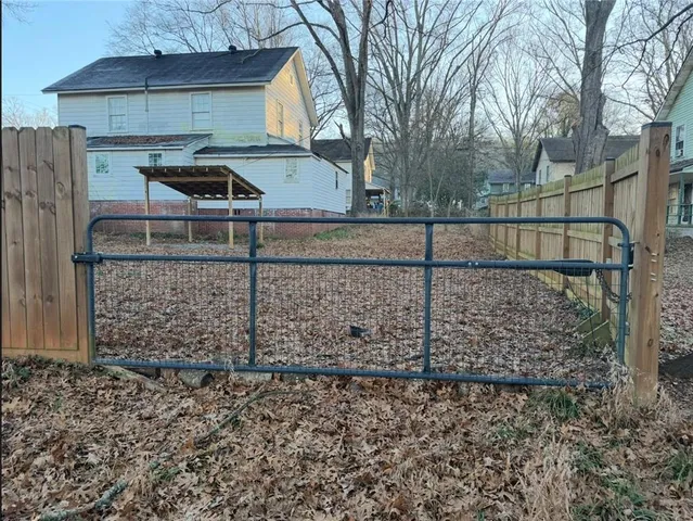 a view of a brick house with a large tree and wooden fence
